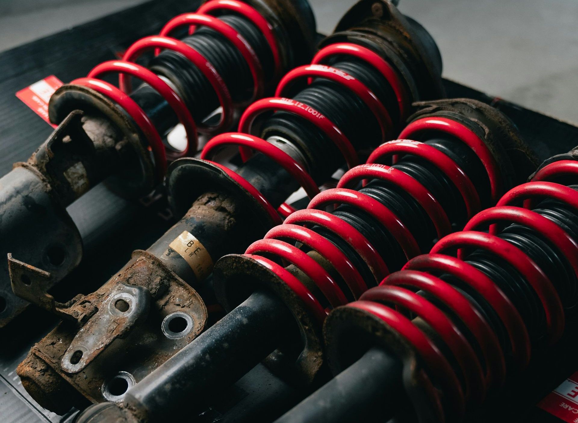Four red coilover suspension assemblies on a black surface